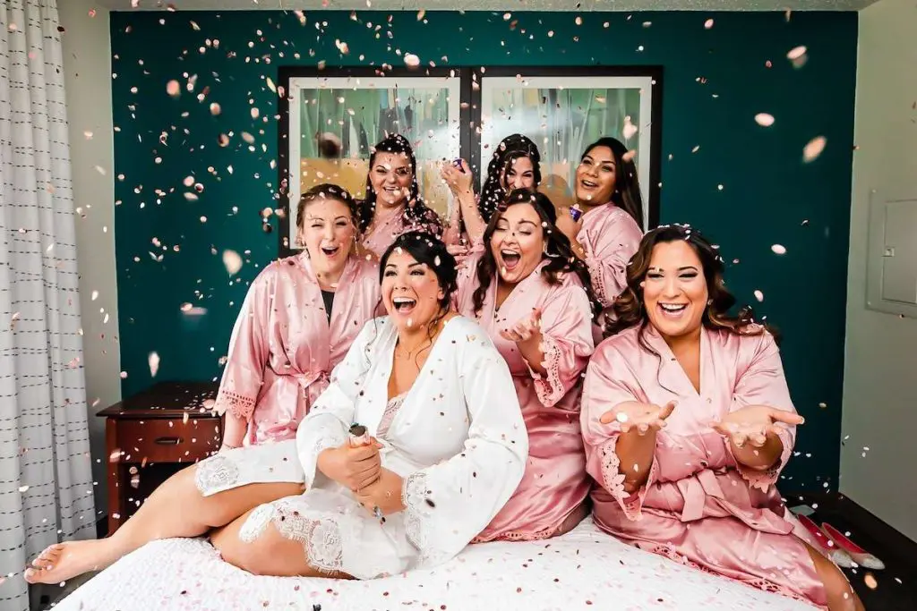 bride and bridesmaids on bed confetti celebrating waterloo village nj wedding