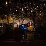 Bride lying on piano with groom sitting in front