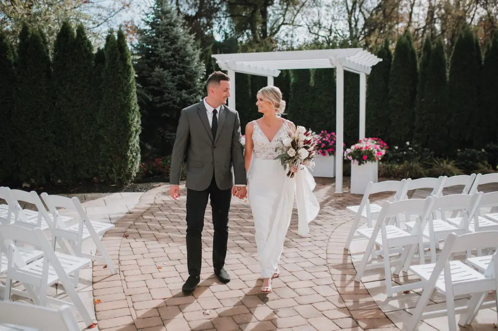 Bride and groom walking on outdoor aisle