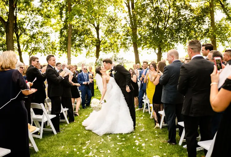 Bride and groom kissing in asle