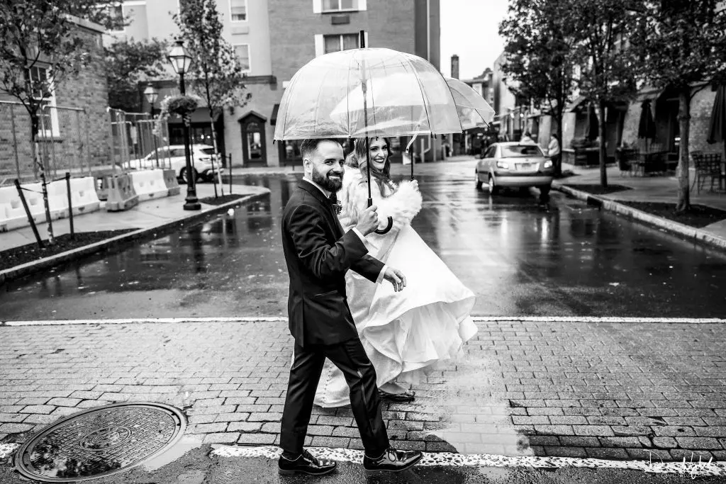 Bride and groom holding umbrella on wedding day at Nassau Inn in Princeton, NJ
