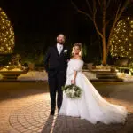 Bride and groom outside at night with lights in trees