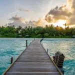 Brown wooden dock on blue sea under white clouds during daytime