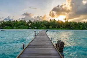 Brown wooden dock on blue sea under white clouds during daytime
